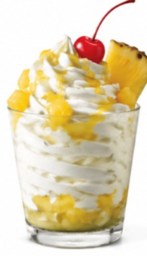 Pineapple shake from the Sonic shake menu topped with whipped cream, pineapple chunks, grilled pineapple, and a cherry in a clear glass.