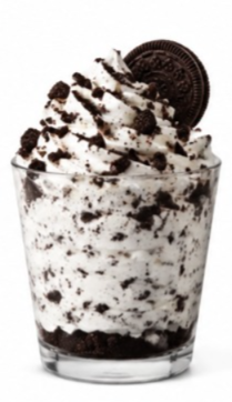 The Oreo Cookies & Cream shake from the Sonic shake menu is topped with whipped cream, crushed Oreo cookie pieces, and a whole Oreo cookie in a clear glass.