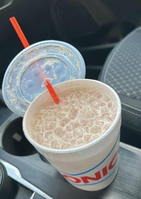 featuring a refreshing iced coffee served in a Sonic cup with ice and a red straw inside a car.